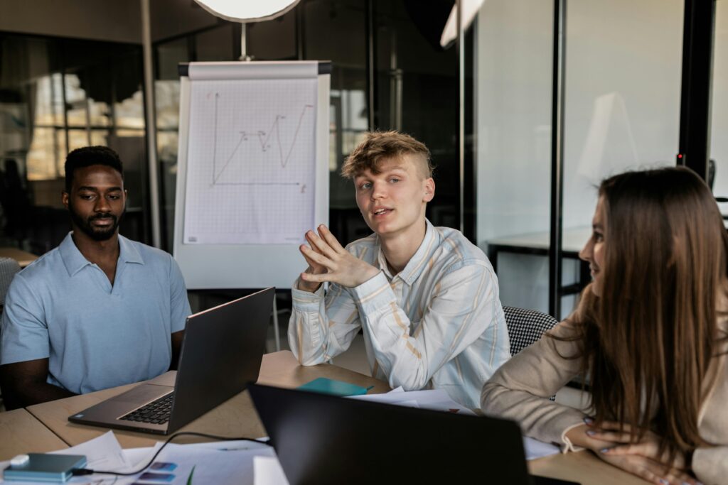 A young professional leading a small team discussion in a business setting.