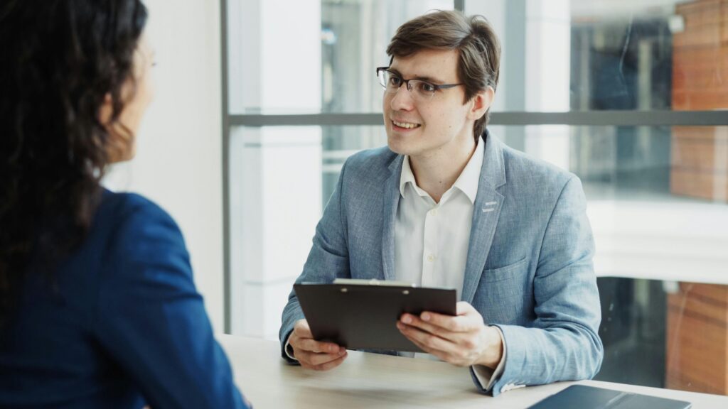 A professional confidently presents ideas in a meeting while engaging in a client conversation.