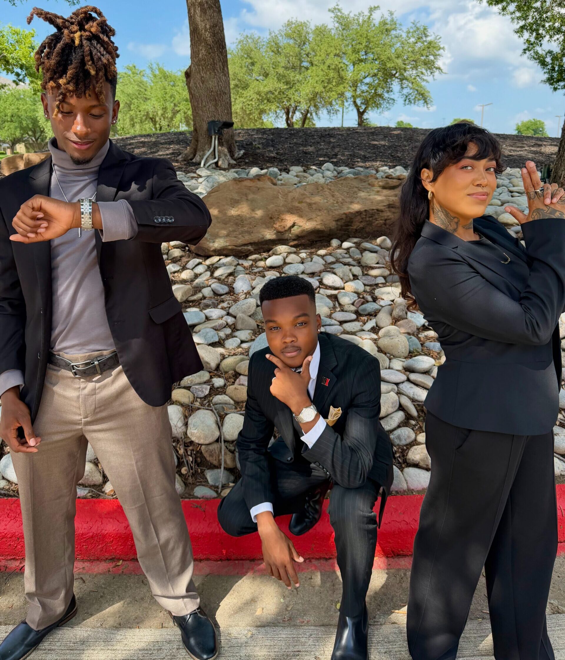 Three professionally dressed team members posing outdoors in confident leadership-style stances.